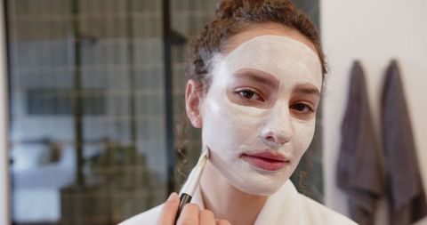 Woman applying facial mask for beauty and skincare at home