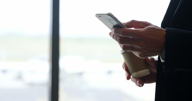 Businessperson Holding Coffee and Smartphone at Airport - Download Free Stock Images Pikwizard.com