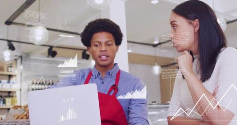 Bakery staff reviewing sales analytics on laptop while consulting customer at counter