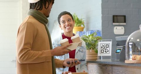 African american customer ordering coffee from friendly barista at qr code cafe counter