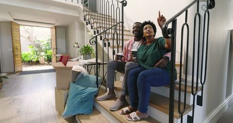 Couple Relaxing on Stairs with Coffee in Renovated Home