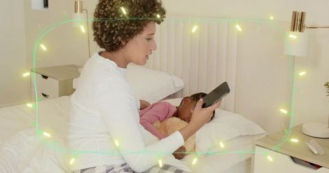 Parent reading bedtime story on tablet while child hugs teddy in cozy nighttime bedroom