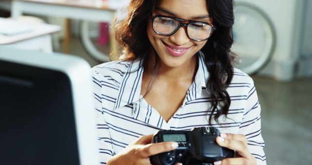 Female Photographer Checking Camera Settings in Office - Download Free Stock Images Pikwizard.com