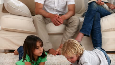 Children Playing on Carpet While Parents Relax on Sofa
