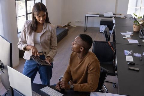 Diverse team collaborating over tablet and desktop in modern open-plan office