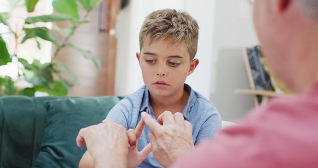 Young boy concentrating while practicing sign language with an instructor. Useful for topics on childhood education, communication skills, language learning, special education, and youth mentoring programs.