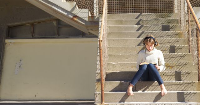 Young Woman Reading a Book on Staircase in Sunlit Outdoors - Download Free Stock Images Pikwizard.com