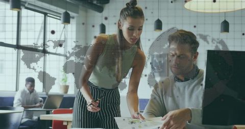 Team collaborating over charts in modern coworking office with world map overlay and daylight