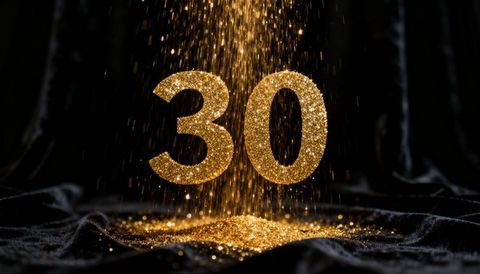 Shimmering gold glitter number 30 falling on black velvet for milestone glamour