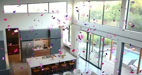 Modern kitchen celebrating with confetti shower over island and pool-view living space
