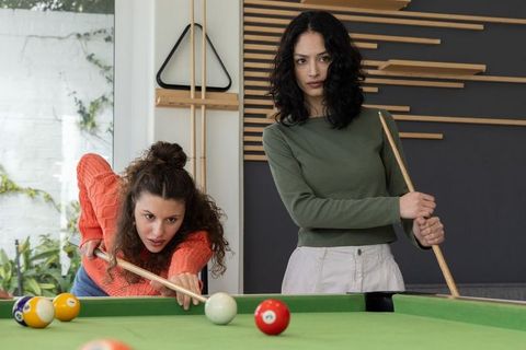 Young women playing pool in modern game room, casual billiards and social leisure