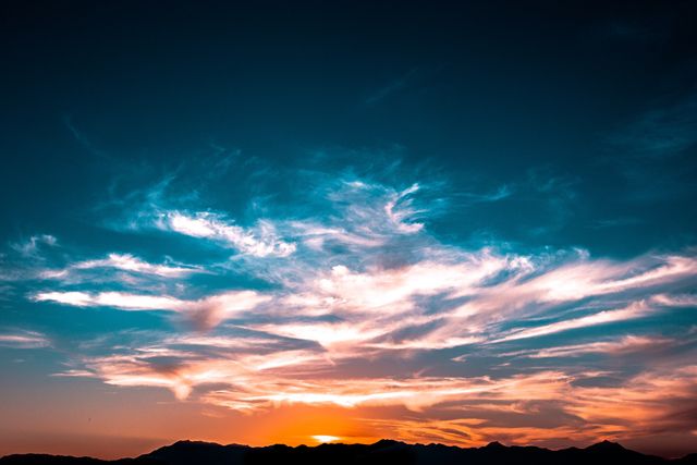 Showing vibrant sunset with colorful clouds over silhouetted mountain range. Ideal for prints, backgrounds, nature blogs, and inspirational content.