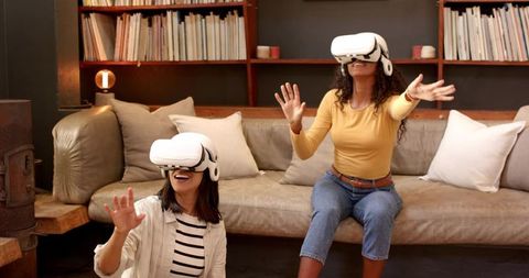 Two Asian Individuals Enjoying VR Experience on Living Room Sofa