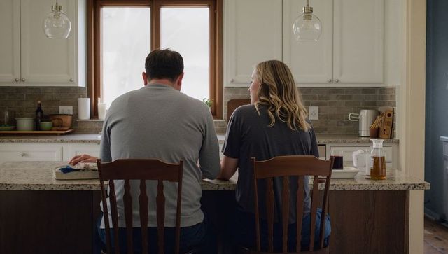 Couple sitting at kitchen island chatting over coffee and papers in cozy home interior