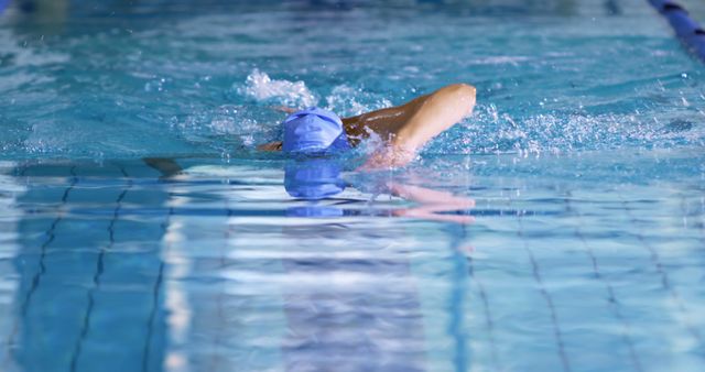 Professional swimmer practices freestyle stroke in blue cap in indoor swimming pool - Download Free Stock Images Pikwizard.com