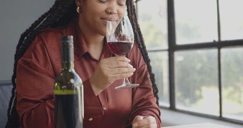 Woman Savoring Red Wine in Elegant Sunlit Room