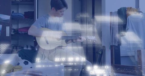 Teen tuning and playing acoustic guitar on bedroom bed with digital light grid overlay