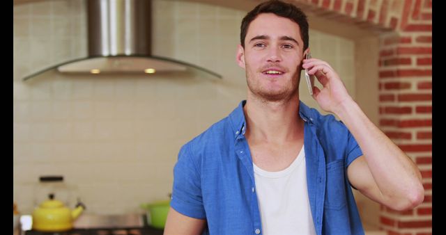 Handsome happy man having a phone call in the kitchen