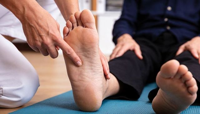 Podiatrist palpating foot sole with index finger during clinical foot assessment