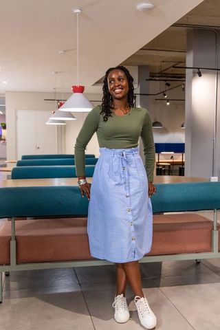 Smiling african american woman posing in modern coworking lounge with pendant lighting