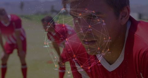 Focused soccer player in red jersey with network overlay highlighting team strategy and performance
