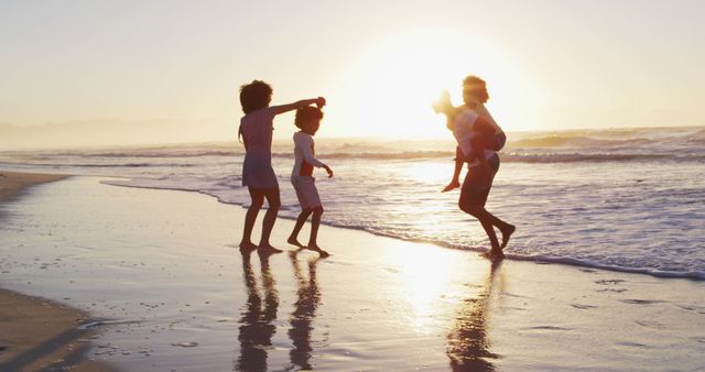 Children enjoy playing near the water's edge as the sun sets. Perfect for articles or advertisements focusing on family vacations, summer activities, outdoor fun, and creating happy memories. Also suitable for use in lifestyle blogs or travel agency promotions.