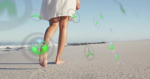 Woman walking barefoot on beach with eco energy icons