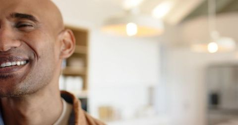 Smiling mature male closeup in modern kitchen with warm pendant lights and copy space
