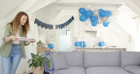 Woman arranging balloons and preparing living room for birthday party