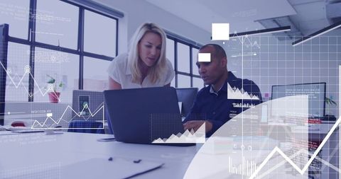 Colleagues reviewing analytics on laptop in modern open-plan office, teamwork