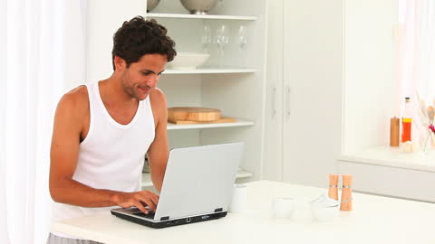 Man Typing on Laptop in Bright Kitchen