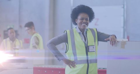 Confident warehouse worker in protective gear standing among boxes