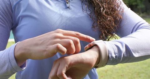 African american female checking smartwatch while tracking run in park wearing light blue top