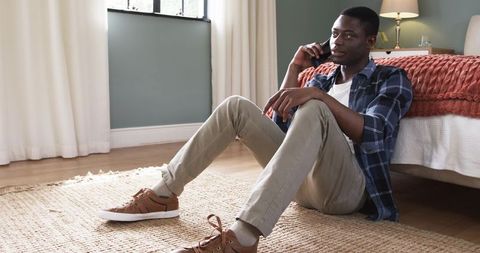 Young Man Relaxing at Home During Phone Call in Modern Bedroom