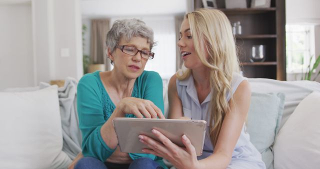 Happy caucasian mother and adult daughter sitting on sofa, using tablet - Download Free Stock Photos Pikwizard.com
