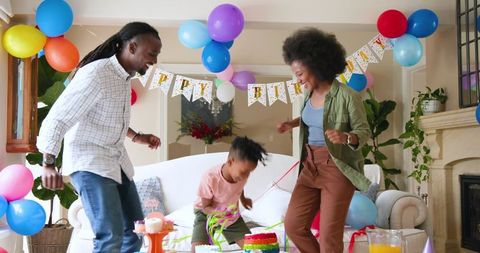 Joyful Family Celebrating Child's Birthday at Home with Dancing and Laughter
