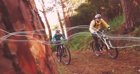 Mountain biking couple riding sunlit pine forest trail with dynamic dotted motion overlay