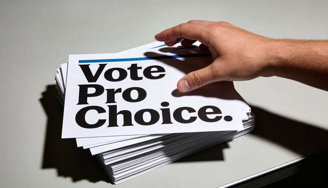 Hand reaching vote pro choice flyers on tabletop dramatic lighting political campaign