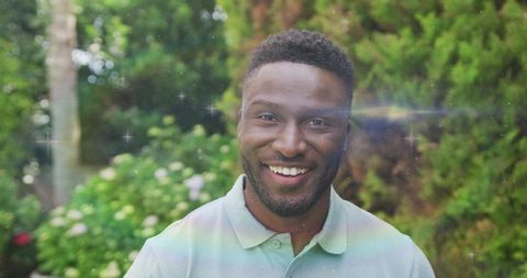 Man Smiling Brightly in Lush Garden with Dreamy Flares