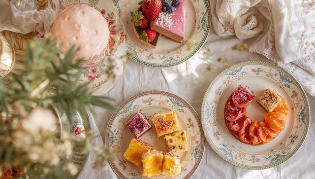 Vintage floral china showcasing assorted petit fours and cheesecakes on linen table