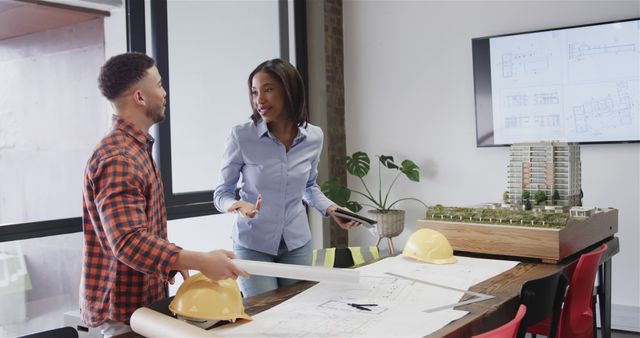 Architects Discussing Building Plans and Scale Model in Modern Office - Download Free Stock Images Pikwizard.com