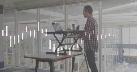 Analyst uses standing desk in modern office to review corporate charts