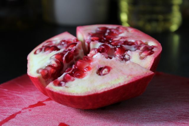 Close-up image of a halved pomegranate showcasing its seeds and juicy interior. Useful for health, nutrition, fresh fruit advertising, recipes featuring pomegranate, and promoting healthy eating habits. Vibrant color can be utilized in promotional materials or health-related articles.