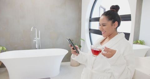 Relaxed Woman in Spa Bathroom Holding Phone and Tea
