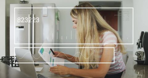 Woman Analyzing Financial Data on Laptop in Modern Kitchen