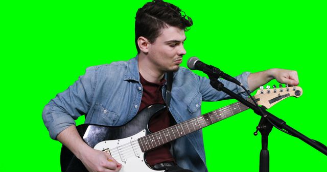 Male musician adjusting tuners against green screen