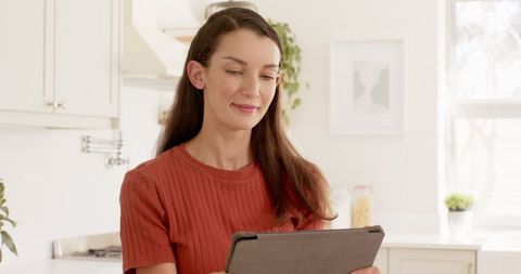 Woman Using Tablet in Modern Minimalist Kitchen Setting