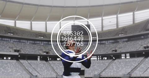 Male athlete raising hands with futuristic circular hud readouts in empty stadium