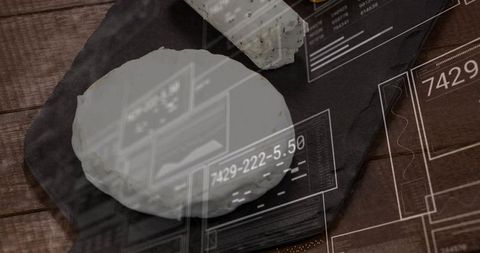 White goat cheese wheel on dark slate with herb log and futuristic hud overlay rustic close-up