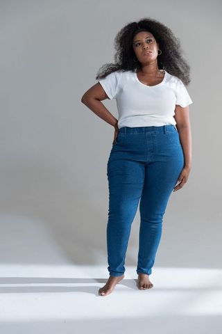 African american woman standing barefoot wearing white tee and high-waisted jeans